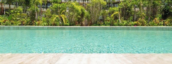 A hotel with a pool surrounded by lush greenery and multiple floors with balconies. - Mistiq Temple II. Loft (Tulum)