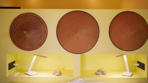 Drei runde Wanddekorationen und zwei Schreibtischlampen mit Mehrfachsteckdose und Steinen an einer gelben Wand.