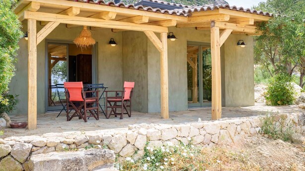 Ein überdachter Außenbereich mit Steinmauern und einer Holzpergola.