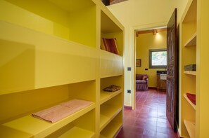 Ein Zimmer mit gelben Regalelementen, einer Holztür und einem Fenster mit Blick.