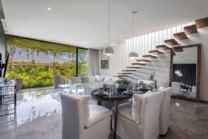 Un salon moderne avec un coin repas, de grandes fenêtres et un escalier.