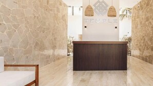 Un área de recepción con pared de piedra, mostrador de recepción y dos lámparas colgantes.
