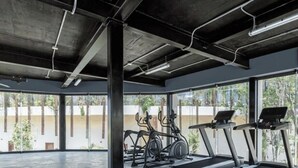 Un gimnasio moderno con cintas de correr, elípticas y un amplio ventanal con vistas al exterior.