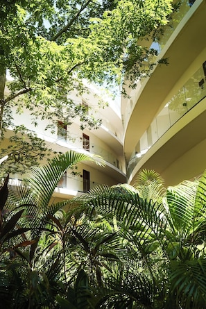 Ein mehrgeschossiges Atrium mit geschwungenen Balkonen und üppiger tropischer Bepflanzung.
