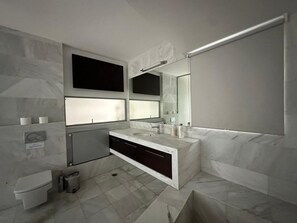 Une salle de bain moderne avec un grand miroir, deux lavabos et des toilettes.