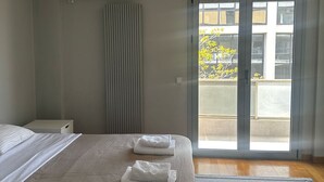 A bedroom with a bed, a radiator, an air conditioning unit, and a sliding glass door leading to a balcony. - Spacious stylish flat at acropolis area! (Athina)