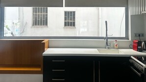 A modern kitchen with a large window, wooden bench, and built-in cabinets. - Spacious stylish flat at acropolis area! (Athina)