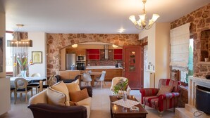 Uma sala de estar espaçosa com lareira, área de jantar e cozinha com armários vermelhos.