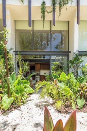 Un bâtiment moderne doté de grandes fenêtres et d’un espace jardin agrémenté de différentes plantes.