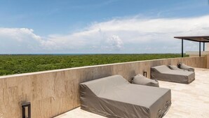 A rooftop terrace with two sun loungers and a covered seating area, overlooking a green landscape. - Spectacular Loft with gym, pool and beach shuttle (Tulum)