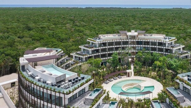 A modern hotel with a central courtyard, multiple swimming pools, and lush greenery surrounding the property. - Spectacular Loft with gym, pool and beach shuttle (Tulum)