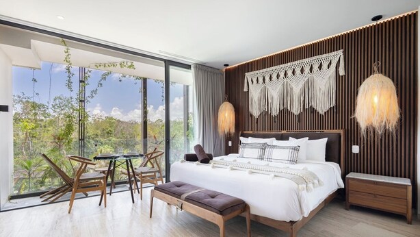 Un dormitorio moderno con una cama grande, una mesa de comedor de vidrio y vistas al exterior.