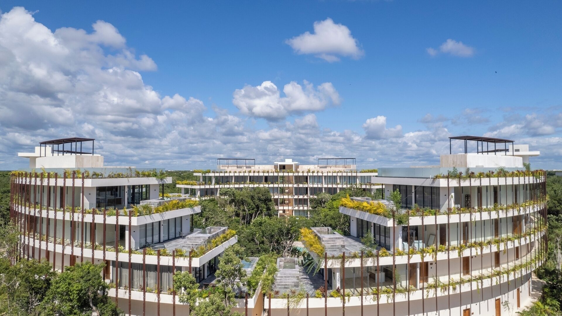 A modern, circular building with multiple floors, large windows, and rooftop gardens.