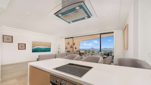 A modern kitchen with a central island, built-in oven, and a large window offering a scenic view. - Bright apartment w/ ocean view and unique decoration (Cabo San Lucas)