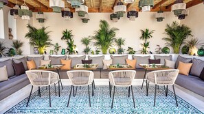 A modern outdoor seating area with wicker chairs, a patterned floor, and hanging pendant lights. - Riad Tamazy  
3-bedroom house in lovely Marrakech with air conditioning (Marrakech)