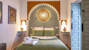 Ein Hotelzimmer mit Bett, grüner Bettwäsche, einer Wandverkleidung und zwei Wandlampen.