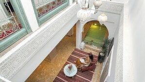 Eine repräsentative Lobby mit hohen Decken, aufwendigen weißen Geländern und einer zentralen Springbrunnen.