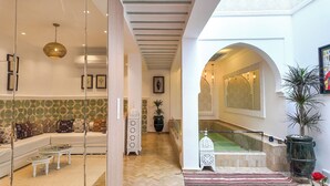 Ein modernes Interieur mit einer Couch, einem Couchtisch und dekorativen Kissen. Eine Treppe bietet Blick auf einen Pool und einen Topfpflanzen.
