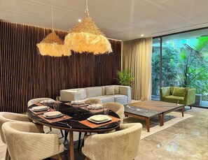 A modern dining area with a round table, chairs, and a sofa. - Character and Comfort at our Luxury Two BD Apart. (Tulum)