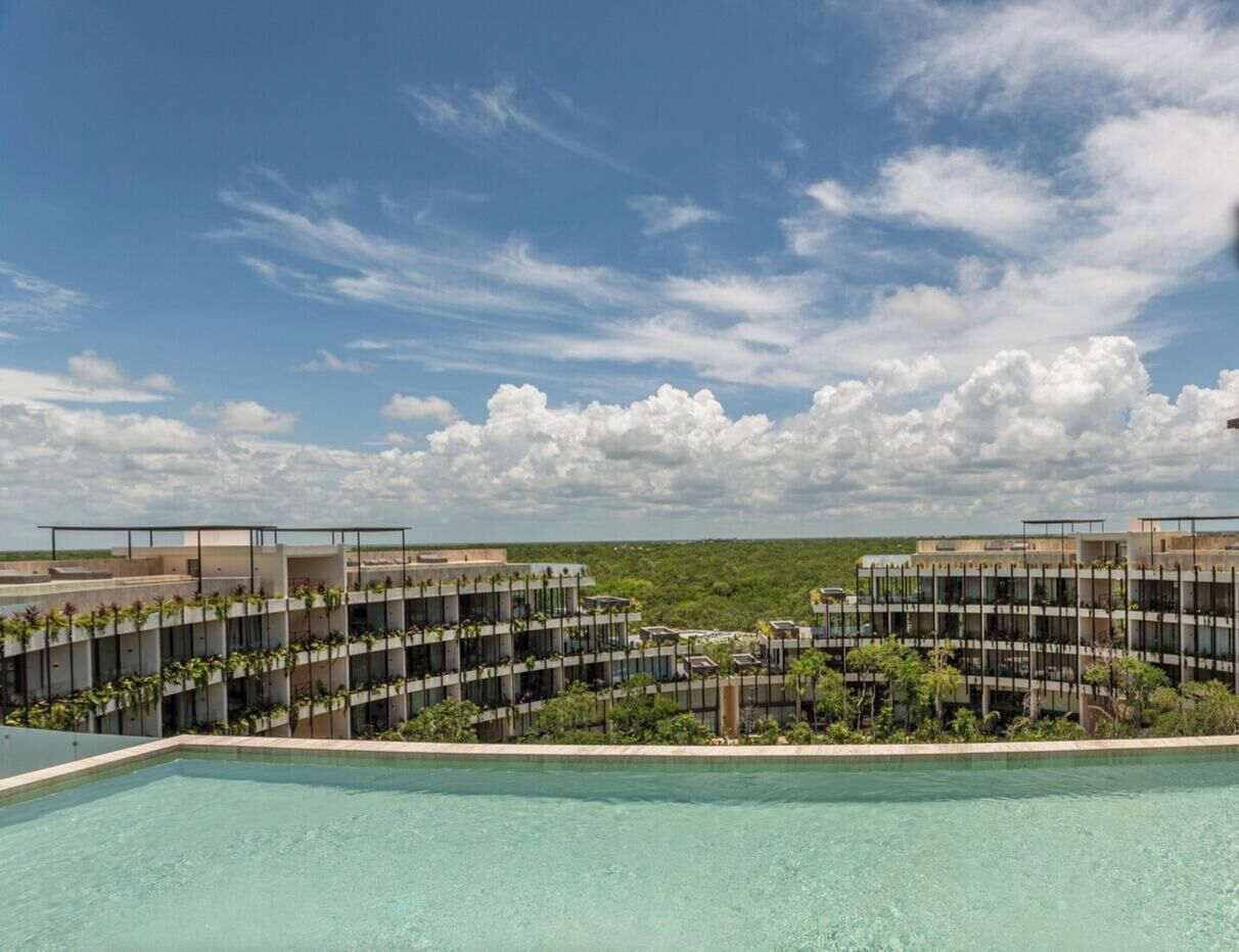 Un hotel modern amb piscina, diverses plantes i vistes al paisatge circumdant.