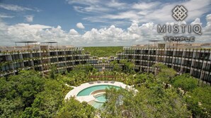 Un hôtel moderne doté d’une piscine centrale, entourée d’une végétation luxuriante et de plusieurs étages de balcons.
