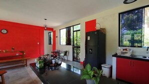 A modern kitchen with a black countertop, red cabinets, and a large window with a view of greenery. - M&K House - Room MK Double first level (Tarapoto)