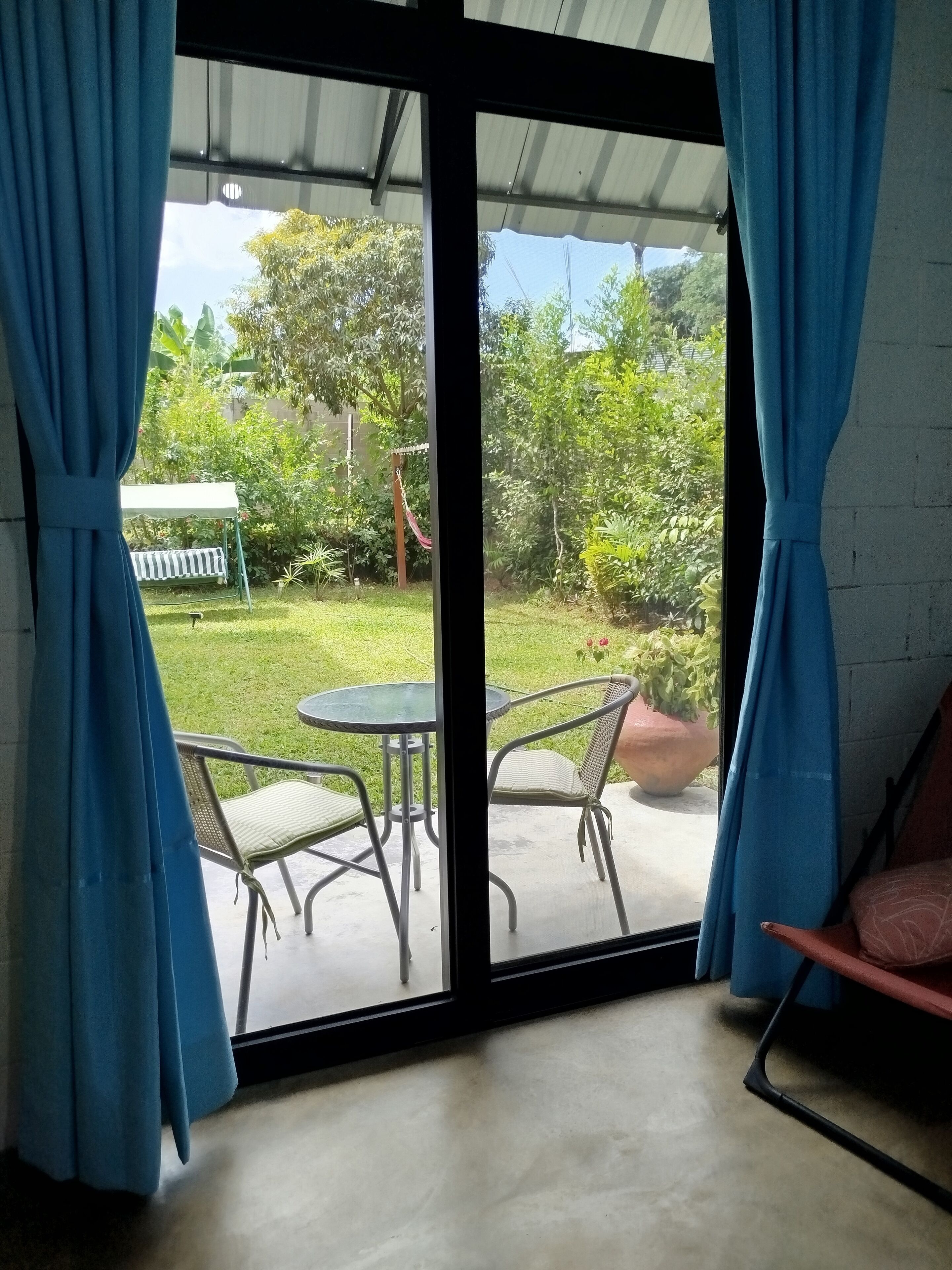 Ein Zimmer mit einer Schiebetür zu einer Terrasse, auf der ein Tisch und Stühle stehen.