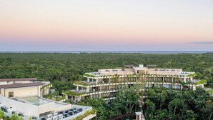 A modern resort with a central building surrounded by lush greenery and a pool area. - One of a kind! Loft with small pool (Tulum)
