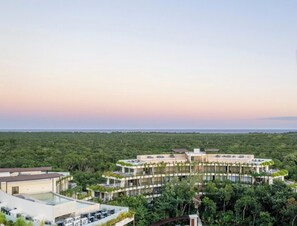 Ein modernes Resort mit einem zentralen Gebäude, umgeben von üppiger Vegetation und einem Poolbereich.