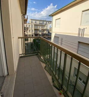 A narrow balcony with a tiled floor, a metal railing, and a view of neighboring buildings. - Apartment in a building facing the sea-Rif. Giglio (San Vincenzo)