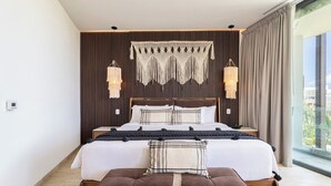 A modern bedroom with a large bed, a wooden bench, and a view of the city through large windows. - Stylish Studio with gym, pool (Tulum)