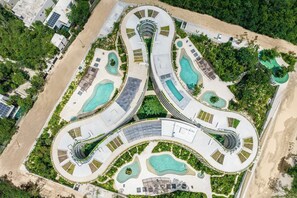 Ein Luftbild eines Resorts mit mehreren Schwimmbecken, geschwungenen Wegen und üppiger Vegetation.