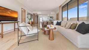 Uma sala de estar moderna com sofá, poltrona, mesa de centro e televisão sobre um móvel.
