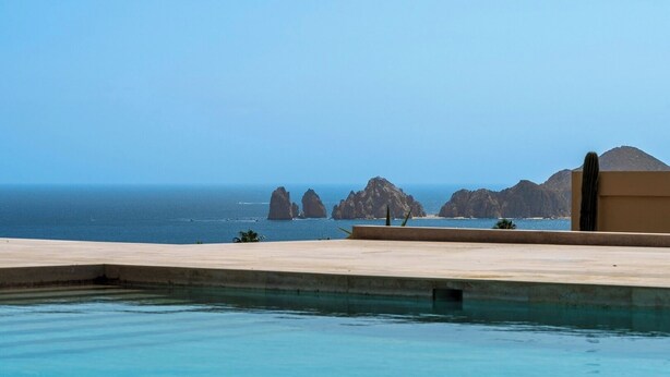 Piscina com vista para o mar e formações rochosas.