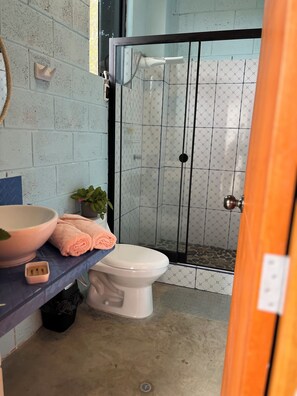Ein Badezimmer mit Dusche, Toilette, Waschbecken, Handtuch und einer Topfpflanze.