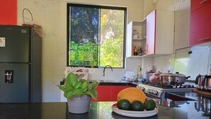 A kitchen with a black countertop, a potted plant, a plate with limes, and a window with a view of greenery. - M&K House - KAR Double Room - 1 or 2 beds (Tarapoto)