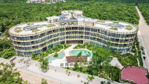 A modern hotel with a curved design, multiple floors, and a central courtyard with a pool. - Jungle view studio, AC, Wifi , Several Pools (Tulum)