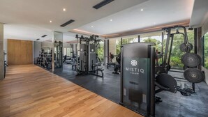 A modern gym with wooden flooring, weightlifting equipment, and large windows offering natural light. - Bright Studio with pool and gym access! 10´from city (Tulum)