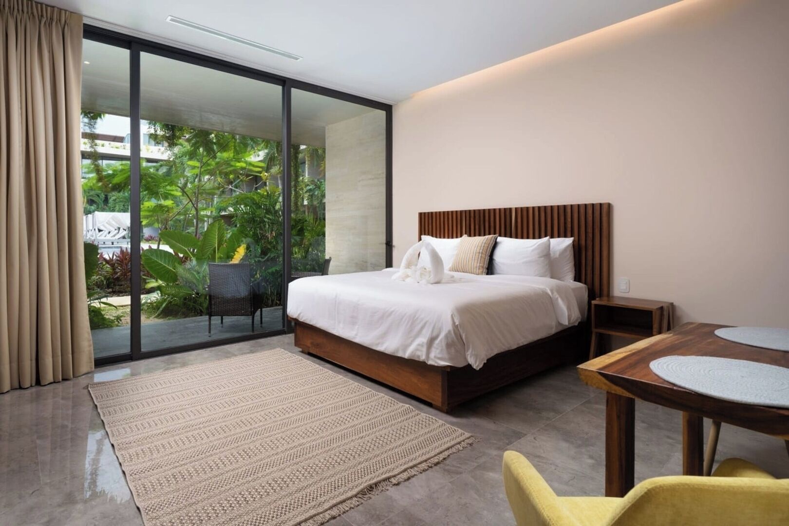 Een moderne slaapkamer met een groot bed, een klein tafeltje en een stoel.