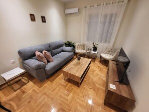 A modern living room with a grey sofa, two armchairs, a coffee table, and a TV stand. - 2 bd renovated flat at acropolis (Athina)