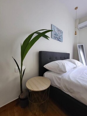A bedroom with a bed, a round wooden table, a potted plant, and a wall-mounted picture. - 2 bd renovated flat at acropolis (Athina)