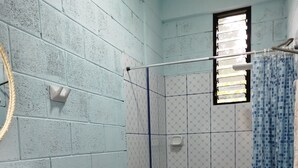 A bathroom with a blue and white tiled wall, a white toilet, a blue sink, and a shower area with a blue curtain. - M&K House - Family JUD Room (Tarapoto)