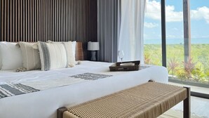 Ett modernt hotellrum med en stor säng, en bänk, ett sängbord och utsikt över omgivningarna.