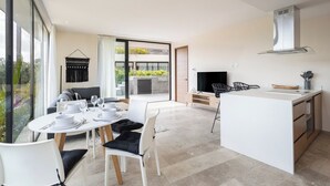 Une cuisine moderne avec un coin repas, de grandes fenêtres et une vue sur la verdure.