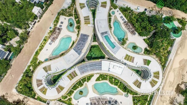 Eine Luftaufnahme eines Resorts mit verbundenen Pools, einem zentralen Gebäude und umgebender Bepflanzung.