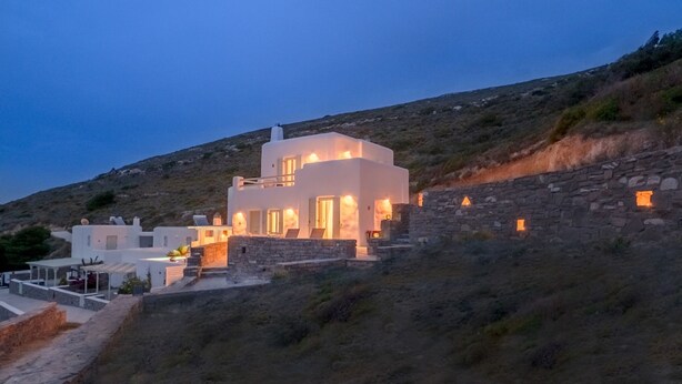 A modern white building with multiple rooms, situated on a hillside with stone walls and a view of the surrounding landscape. - Casa Thymus , great sea view (Agios Charalampos)
