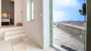 A modern interior with a staircase leading to a balcony with a stone wall and a view of the landscape. - Casa Thymus , great sea view (Agios Charalampos)