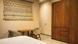 Habitación de hotel con una cama, un armario de madera, una mesita y una silla.