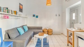 Una sala de estar moderna con un sofá gris, una pequeña mesa blanca, cestos de mimbre y un lámpara colgante.