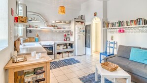 Una cocina moderna con armarios blancos, horno empotrado y comedor con mesa de madera y alfombra azul.